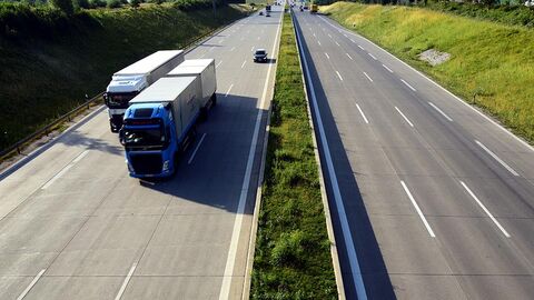 Autobahn von einer Brücke aus betrachtet, zwei Lastwagen kommen entgegen.