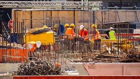Mehrere Bauarbeiter arbeiten auf einer größeren Baustelle.