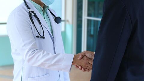 Arzt (Symbolbild) Bildausschnitt - Arzt beim Handschlag mit einem Mann im Anzug