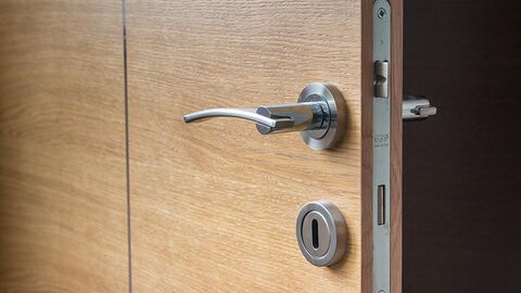 Ausschnitt aus einer Wohnungstür mit Klinke und Schloss.