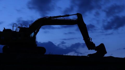 Silhouette eines Baggers vor dem nächtlichen Himmel.