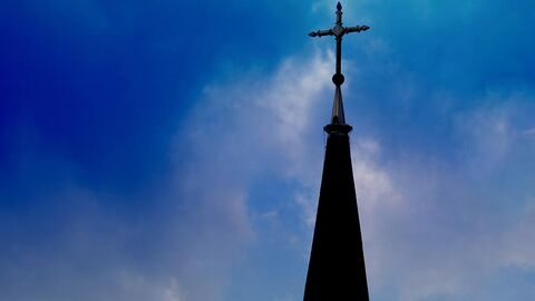 Kirchturmspitze, im Hintergrund Himmel mit Gewitterstimmung.