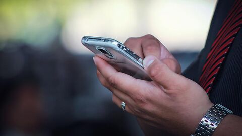 Zwei Hände, die ein Mobiltelefon bedienen.