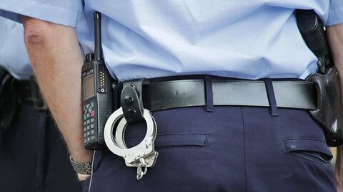 Polizist Polizist von hinten, Ausschnitt Körpermitte mit Handschellen und Waffe am Gürtel.