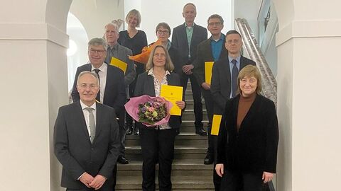 Ernennung Vorsitzende Richterinnen und Richter Die ernannten Richterinnen und Richter stehen gemeinsam mit Justizministerin Kühne-Hörmann in einem Torbogen, nach hinten auf Stufen verteilt und lächeln in die Kamera.