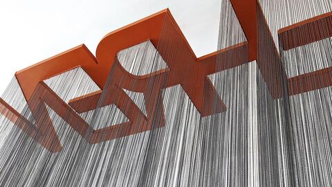 Ausstellungsstück "Don't Touch" Helle Fläche mit diagonal aufsteigenden roten Blockbuchstaben. Wie Schatten fallen schwarze Striche aus den Buchstaben auf den Betrachter zu.