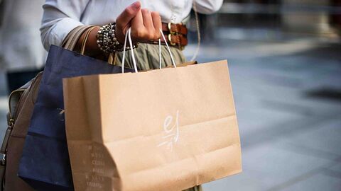 Frau trägt zwei Einkaufstaschen aus Papier.