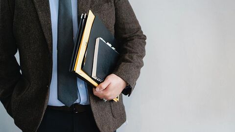 Mann trägt Akten unter seinem Arm.