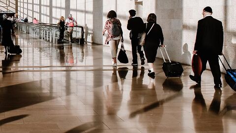 Personen mit Gepäck gehen einen Flur im Flughafen entlang.