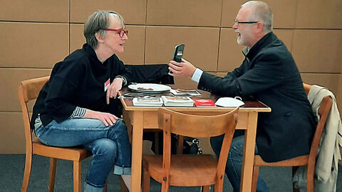 Gudrun Emmert und Mathias Weis Gudrun Emmert und Mathias Weis sitzen an einem Tisch und kommunizieren.