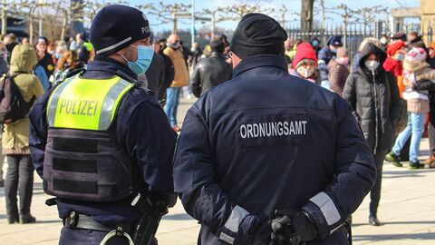 Zwei Polizisten von hinten zu sehen stehen vor einer Menschenmenge