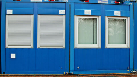 Zwei blaue Wohncontainer stehen nebeneinander.
