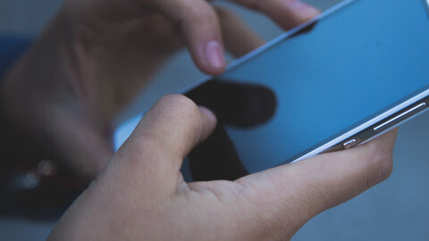 Hände bearbeiten ein Smartphone.