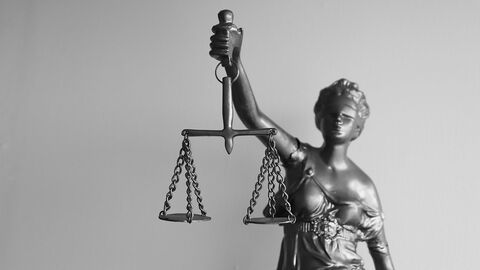 Justitia-Statue hält eine Waage in einer Hand.