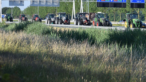Eine Reihe von Traktoren blockieren eine Autobahn.