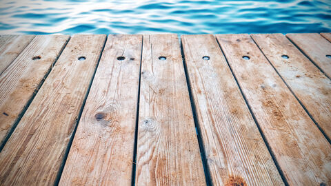 Teil eines hölzernen Pontons, im Hintergrund Wasser.