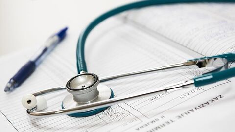 Stethoskop und ein Kugelschreiber liegen auf einem aufgeschlagenen Buch