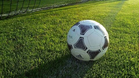 Ein Fußball liegt auf einem Fußballfeld.