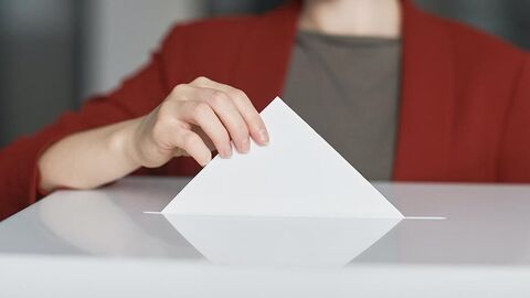 Eine Frau wirft einen Wahlzettel in eine Wahlurne.