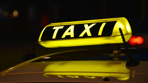 Leuchte mit der Beschriftung TAXI auf einem Kfz bei Nacht.